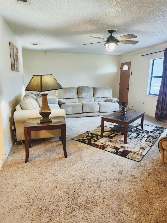 carpeted living room featuring ceiling fan and a textured ceiling