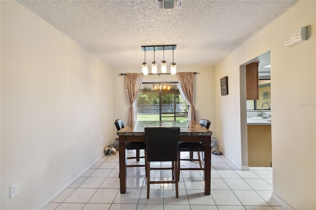 dining space with light tile patterned floors, sink, and a textured ceiling