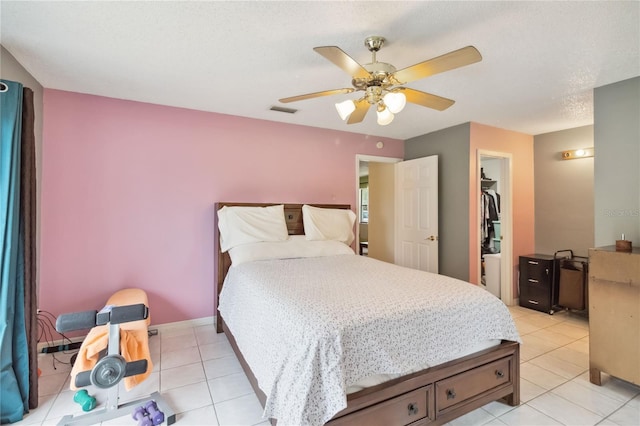 bedroom with a walk in closet, light tile patterned floors, ceiling fan, and a closet