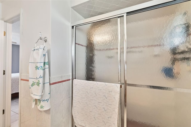 bathroom featuring a shower with door and tile walls