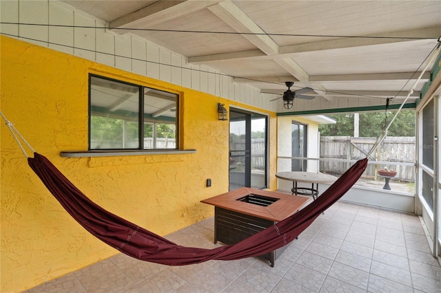 unfurnished sunroom featuring ceiling fan and beam ceiling