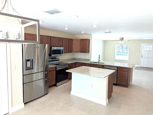 6921 Central Ave, Mulberry, FL 33860 - kitchen featuring appliances with stainless steel finishes, a sink, a peninsula, light stone counters, and a kitchen island