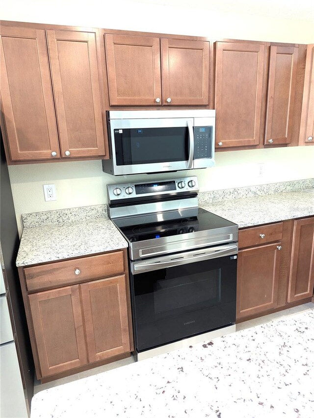 6921 Central Ave, Mulberry, FL 33860 - kitchen with stainless steel appliances, light stone counters, and brown cabinetry