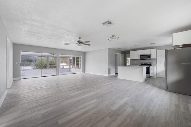 unfurnished living room with a textured ceiling, light wood-type flooring, and ceiling fan