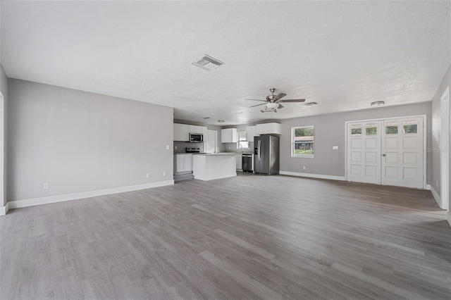 unfurnished living room with light hardwood / wood-style flooring, a textured ceiling, and ceiling fan