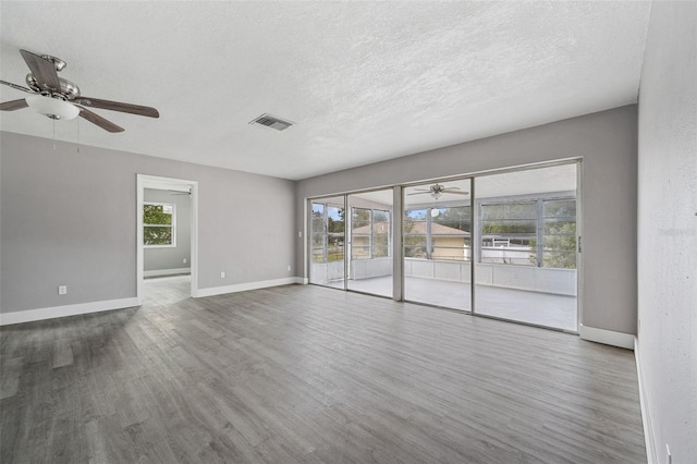 unfurnished room with ceiling fan, a textured ceiling, and dark hardwood / wood-style flooring