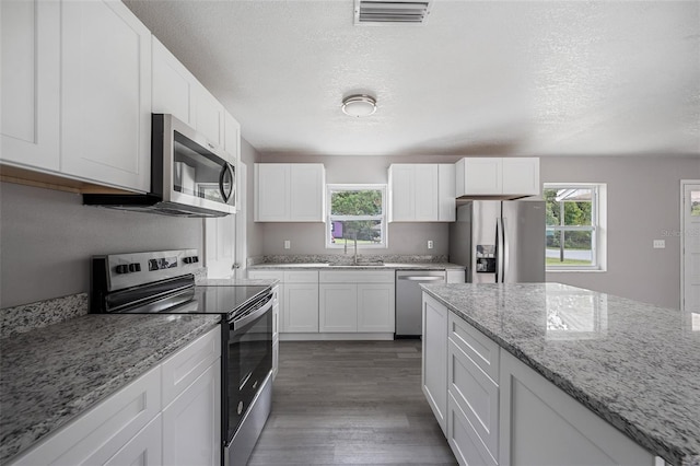 kitchen featuring stainless steel appliances, a textured ceiling, dark hardwood / wood-style floors, sink, and white cabinets