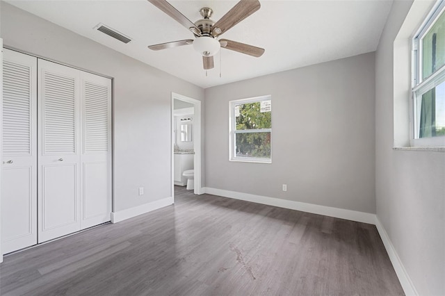 unfurnished bedroom with a closet, hardwood / wood-style flooring, ceiling fan, and ensuite bath