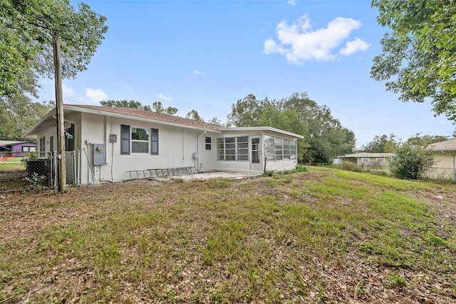 rear view of house featuring a sunroom and a lawn