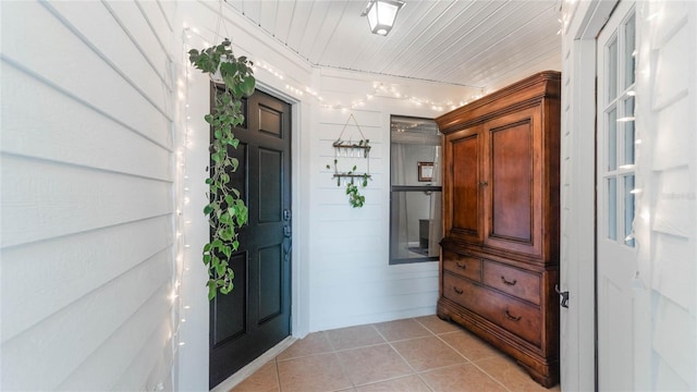 interior space featuring light tile patterned floors, wooden ceiling, and wood walls