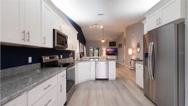 kitchen with kitchen peninsula, appliances with stainless steel finishes, light hardwood / wood-style flooring, white cabinets, and lofted ceiling