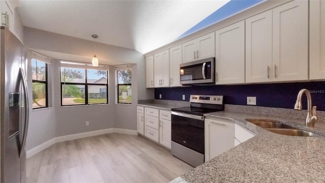 kitchen with sink, white cabinets, stainless steel appliances, and decorative light fixtures