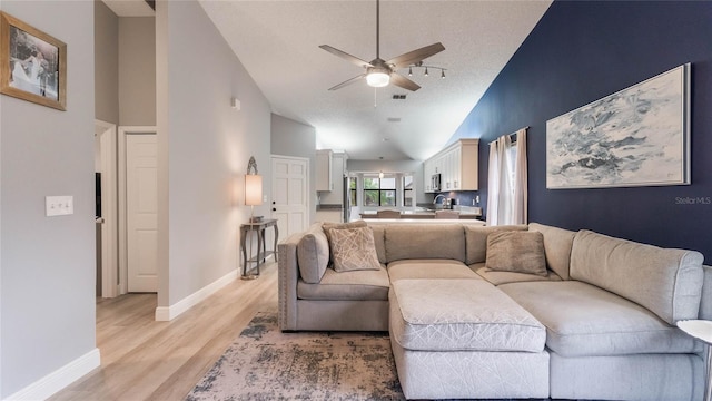 living room featuring ceiling fan, high vaulted ceiling, and light wood-type flooring