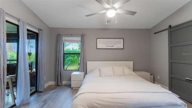 bedroom featuring access to exterior, light wood-type flooring, ceiling fan, a barn door, and lofted ceiling