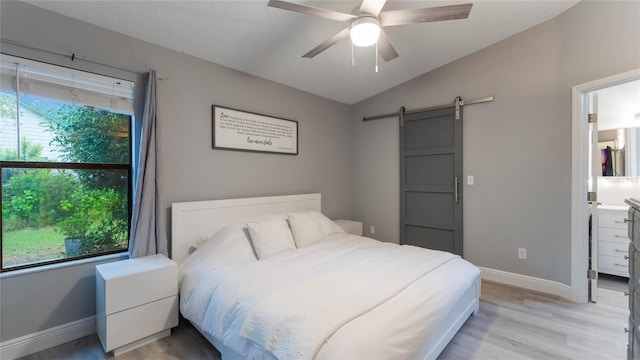 bedroom featuring multiple windows, a barn door, vaulted ceiling, and ceiling fan