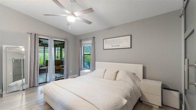 bedroom with a textured ceiling, access to outside, vaulted ceiling, ceiling fan, and light hardwood / wood-style floors