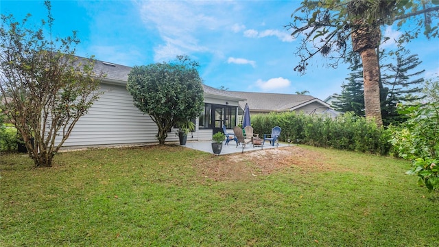 rear view of property featuring a patio, a sunroom, and a lawn