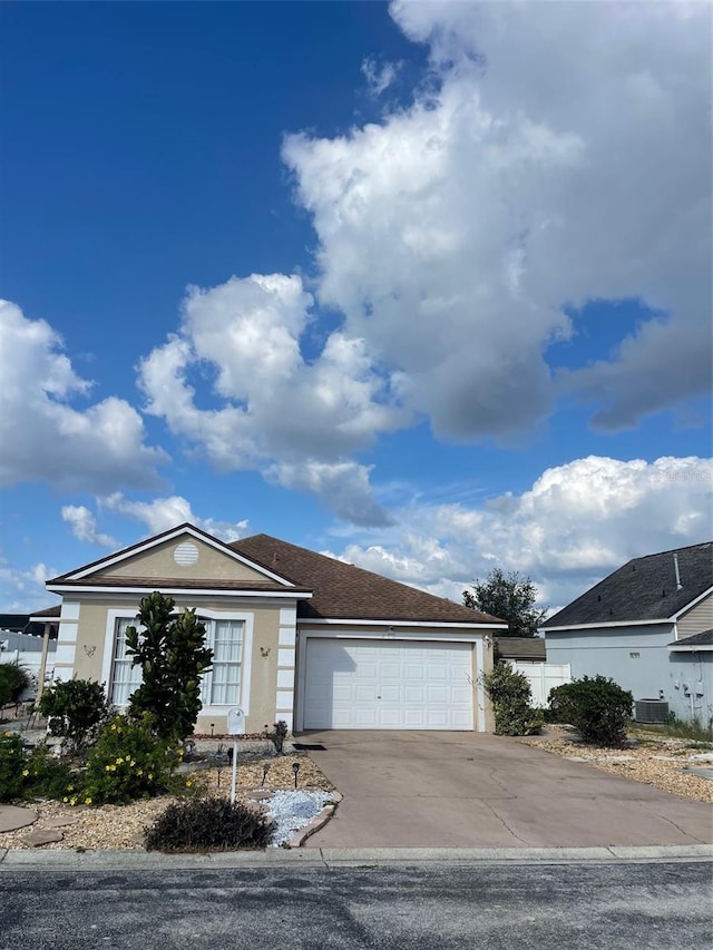 ranch-style home with central AC unit and a garage