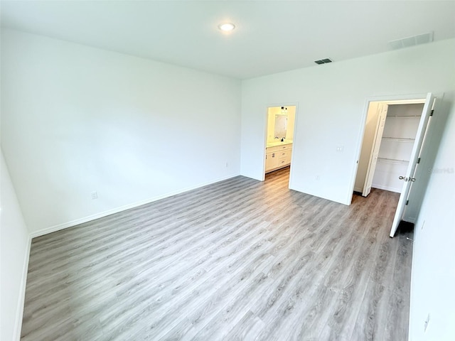 1294 Napoleon Rd, North Port, FL 34288 - unfurnished bedroom with light wood-style floors, recessed lighting, a walk in closet, baseboards, and connected bathroom