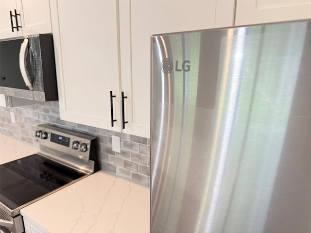 1294 Napoleon Rd, North Port, FL 34288 - kitchen featuring appliances with stainless steel finishes, decorative backsplash, white cabinetry, and light stone countertops