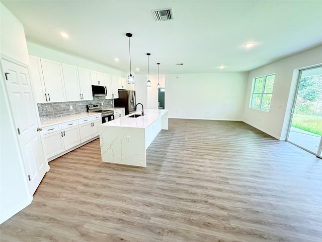 1294 Napoleon Rd, North Port, FL 34288 - kitchen with stainless steel appliances, a center island with sink, a sink, light wood-style flooring, and light countertops