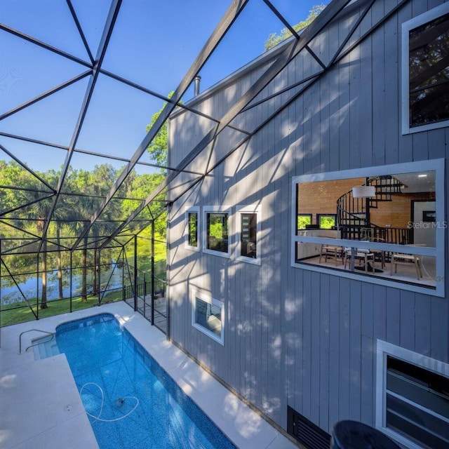 outdoor pool featuring glass enclosure and a patio area