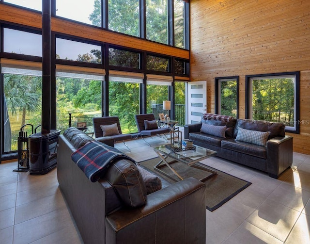 living area featuring tile patterned floors, wooden walls, plenty of natural light, and a high ceiling