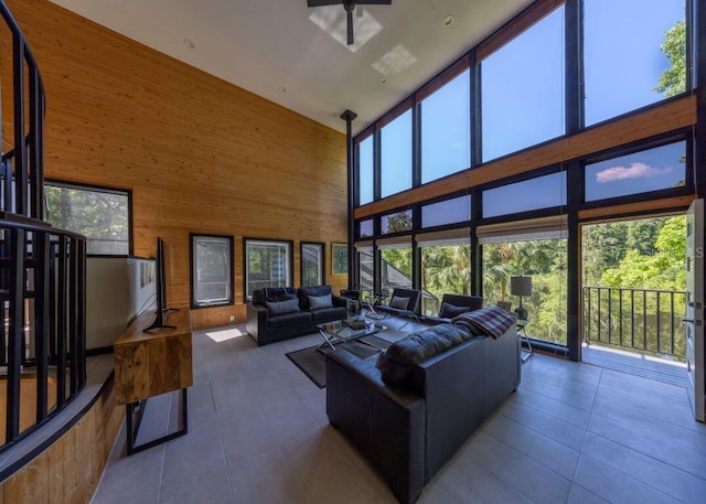 living area with floor to ceiling windows, tile patterned flooring, wood walls, and a healthy amount of sunlight