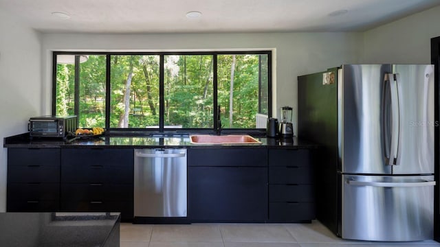 kitchen featuring light tile patterned floors, a toaster, a sink, stainless steel appliances, and modern cabinets