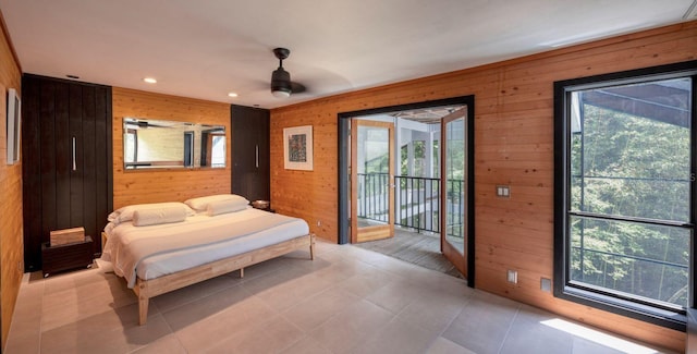 bedroom featuring access to exterior, light tile patterned floors, recessed lighting, and wood walls