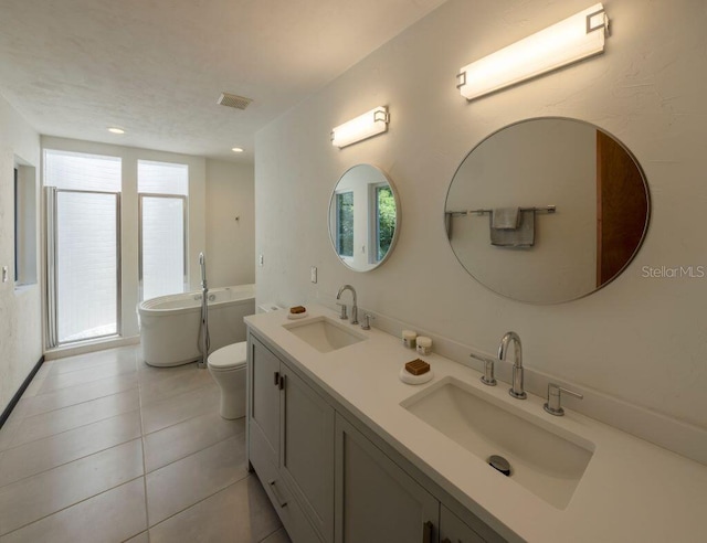 bathroom with double vanity, a freestanding tub, visible vents, and a sink