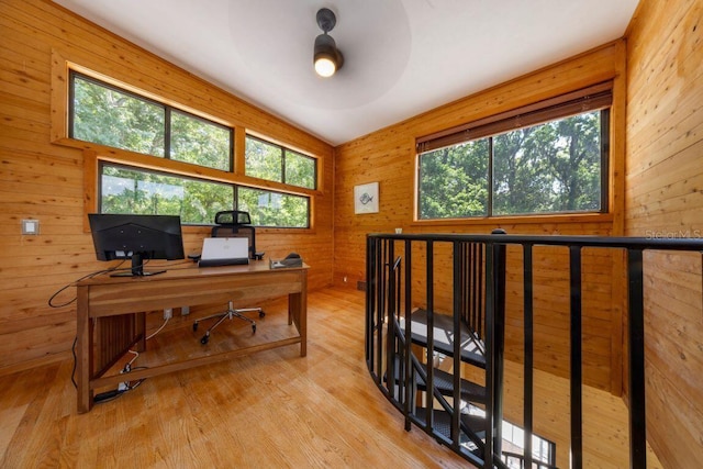 home office featuring a wealth of natural light, wooden walls, ceiling fan, and light wood-style floors