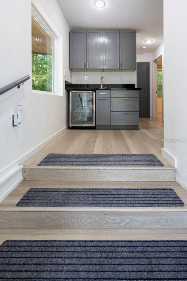 kitchen featuring beverage cooler, gray cabinets, and light wood-style flooring