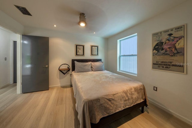 bedroom with light wood-style floors, visible vents, and baseboards