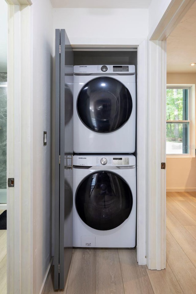 laundry room with laundry area, stacked washer / dryer, and wood finished floors