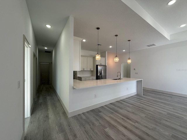 kitchen with sink, hanging light fixtures, stainless steel fridge with ice dispenser, hardwood / wood-style floors, and white cabinets