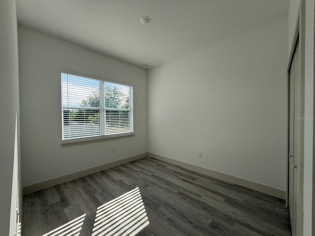 unfurnished room with dark wood-type flooring