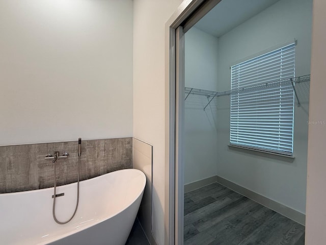 bathroom with a washtub and wood-type flooring