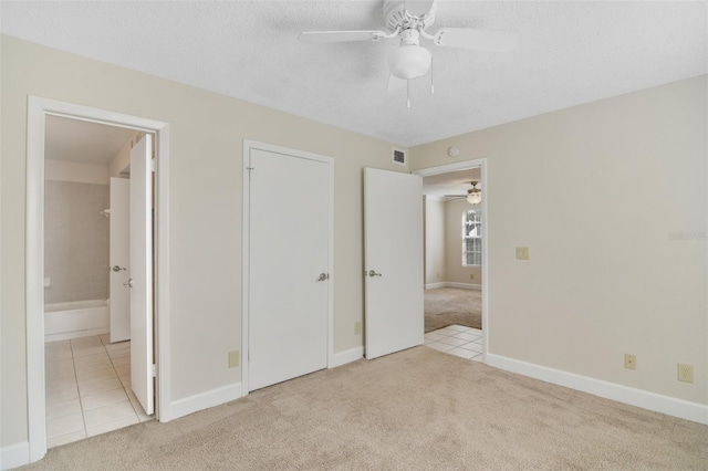 unfurnished bedroom featuring tile patterned flooring, a textured ceiling, visible vents, and carpet flooring