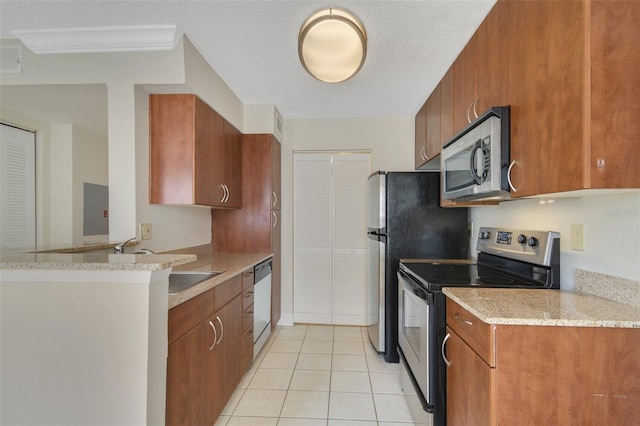 kitchen featuring light tile patterned floors, brown cabinetry, light stone counters, appliances with stainless steel finishes, and a sink