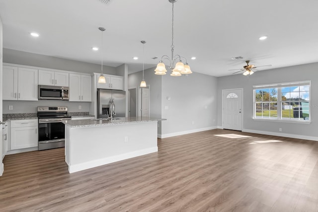 kitchen featuring an island with sink, pendant lighting, white cabinets, and stainless steel appliances