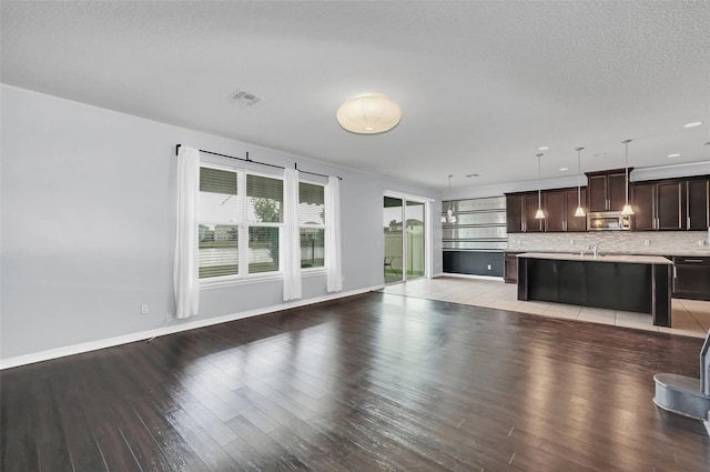 unfurnished living room with a textured ceiling, light hardwood / wood-style flooring, and sink