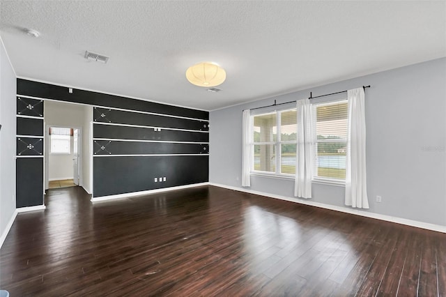 unfurnished room featuring dark hardwood / wood-style flooring and a textured ceiling