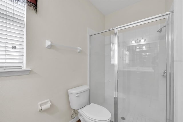 bathroom featuring toilet and a shower with door