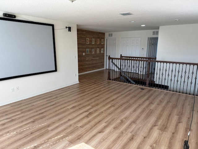 interior space with a textured ceiling, light hardwood / wood-style flooring, and wood walls