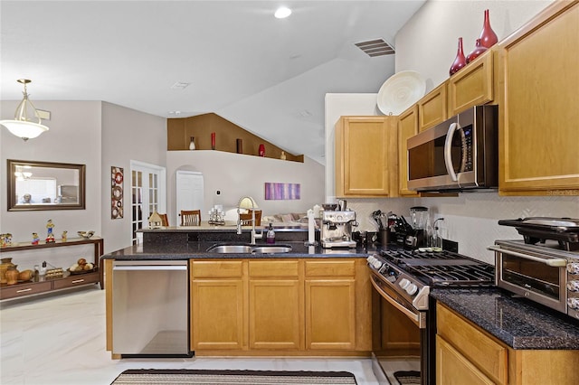 kitchen featuring stainless steel appliances, sink, dark stone counters, decorative light fixtures, and vaulted ceiling