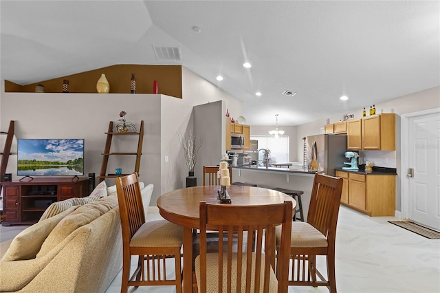 dining area with a notable chandelier, sink, and vaulted ceiling