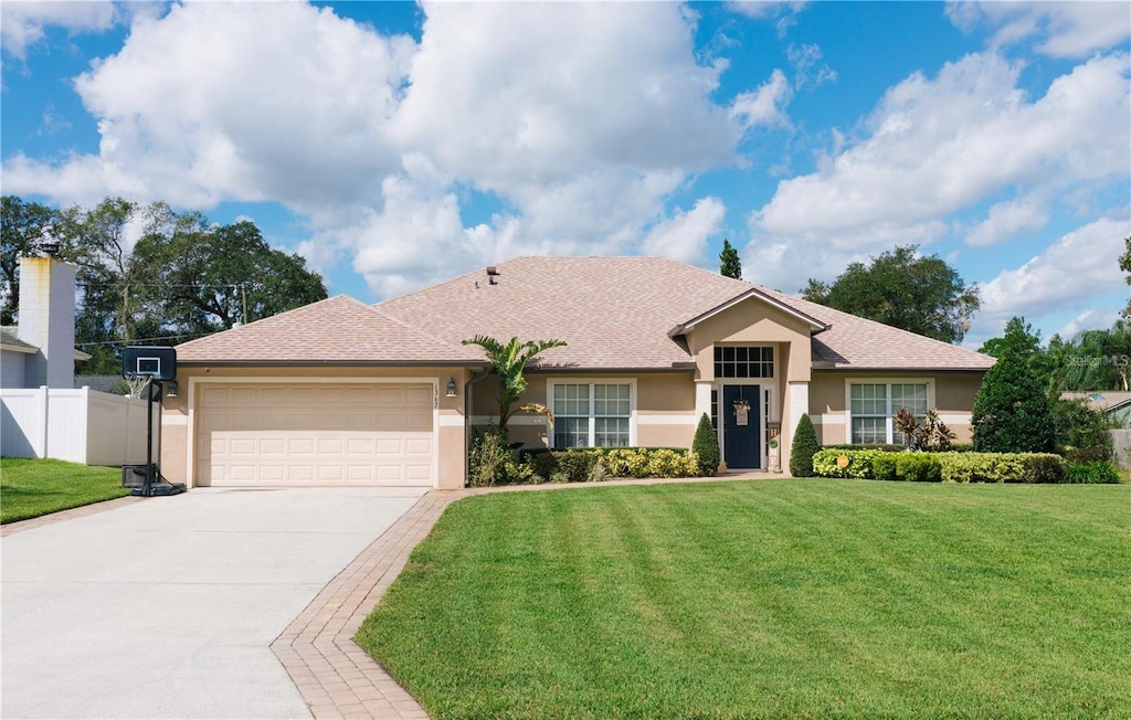 ranch-style house featuring a garage and a front lawn