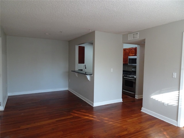 unfurnished room featuring a textured ceiling, dark hardwood / wood-style flooring, and sink