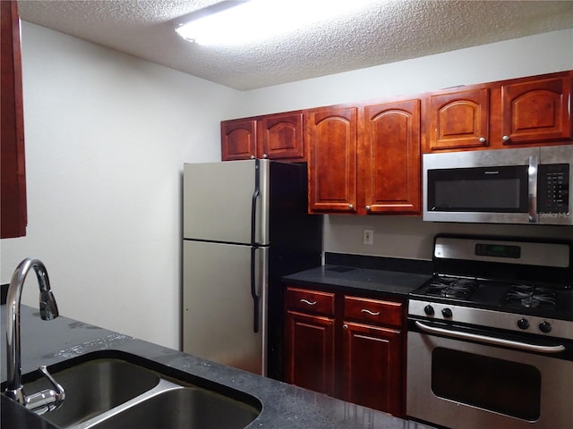 kitchen with a textured ceiling, stainless steel appliances, and sink